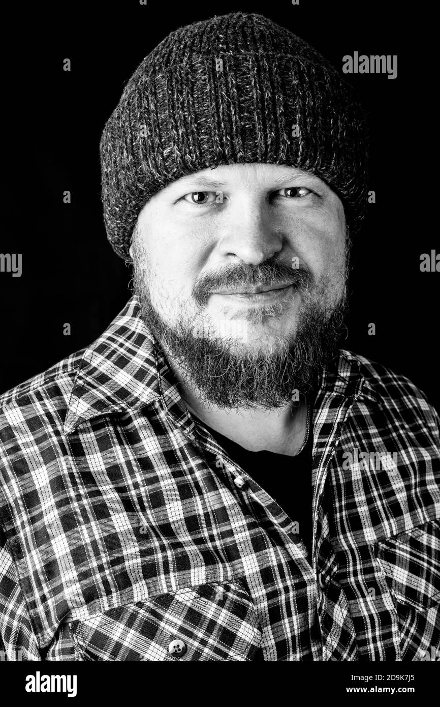 Solid bearded man in a wool cap portrait on black background Stock Photo