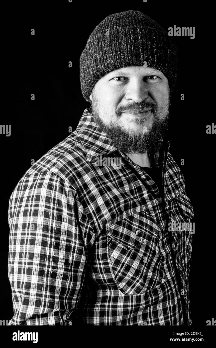 Solid bearded man in a wool cap portrait on black background Stock Photo