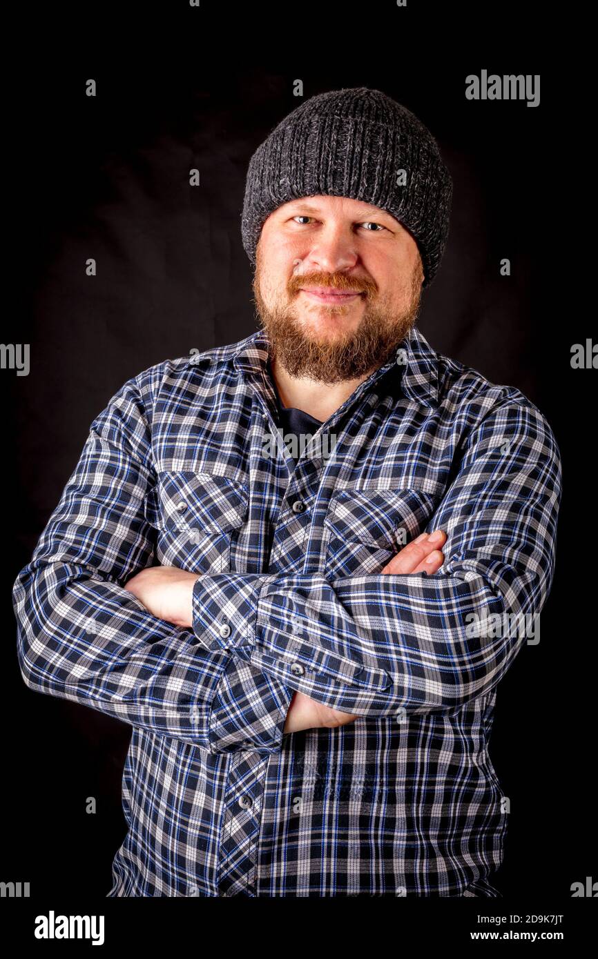 Solid bearded man in a wool cap portrait on black background Stock Photo