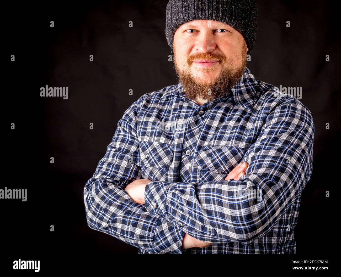Solid bearded man in a wool cap portrait on black background Stock Photo