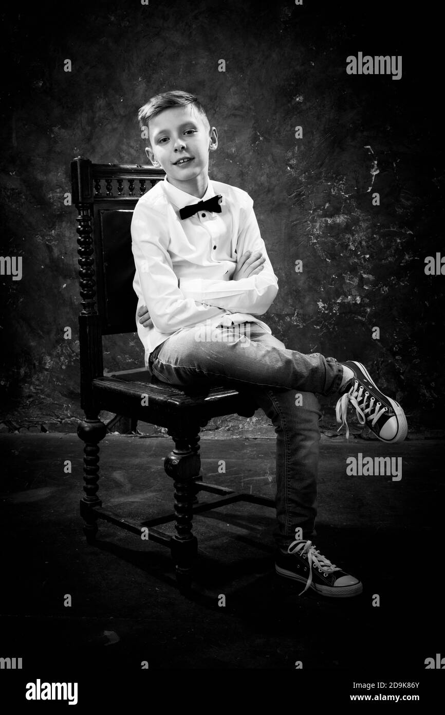 Young cheerful boy sitting on chair studio portrait Stock Photo Alamy