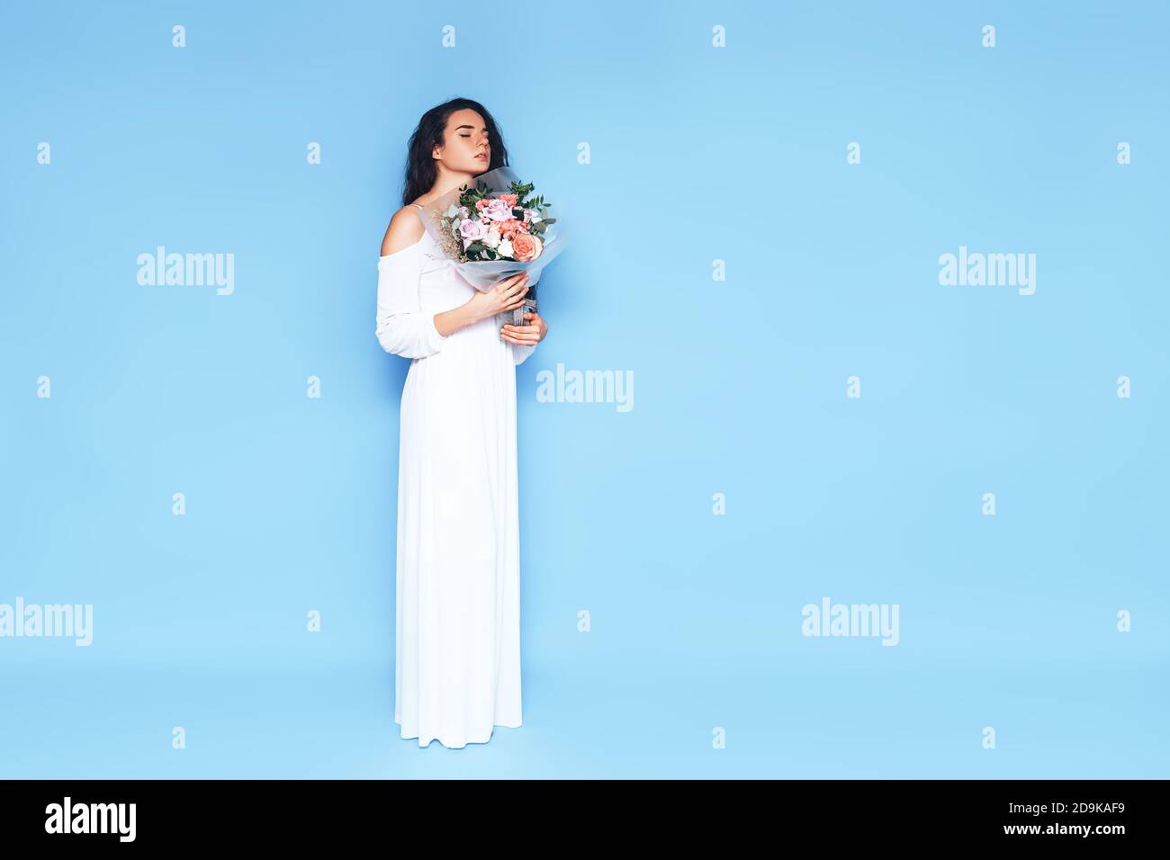 Young woman in white dress holding a beautiful bouquet of roses ...