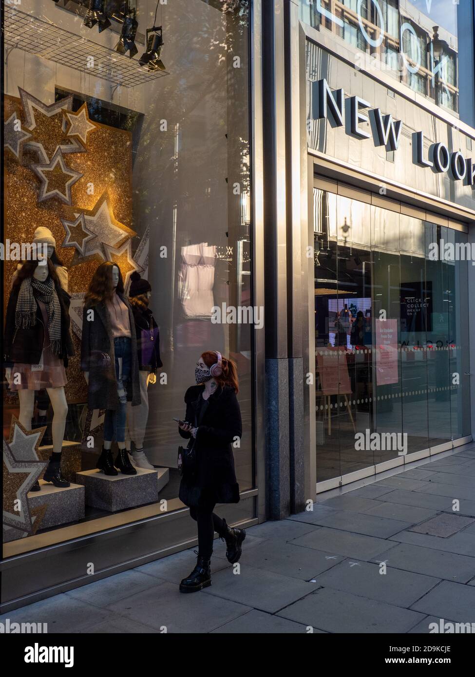 NEW LOOK: A person wearing a face mask passes a New Look store on Oxford Street closed on the first Saturday of lockdown 2. Stock Photo