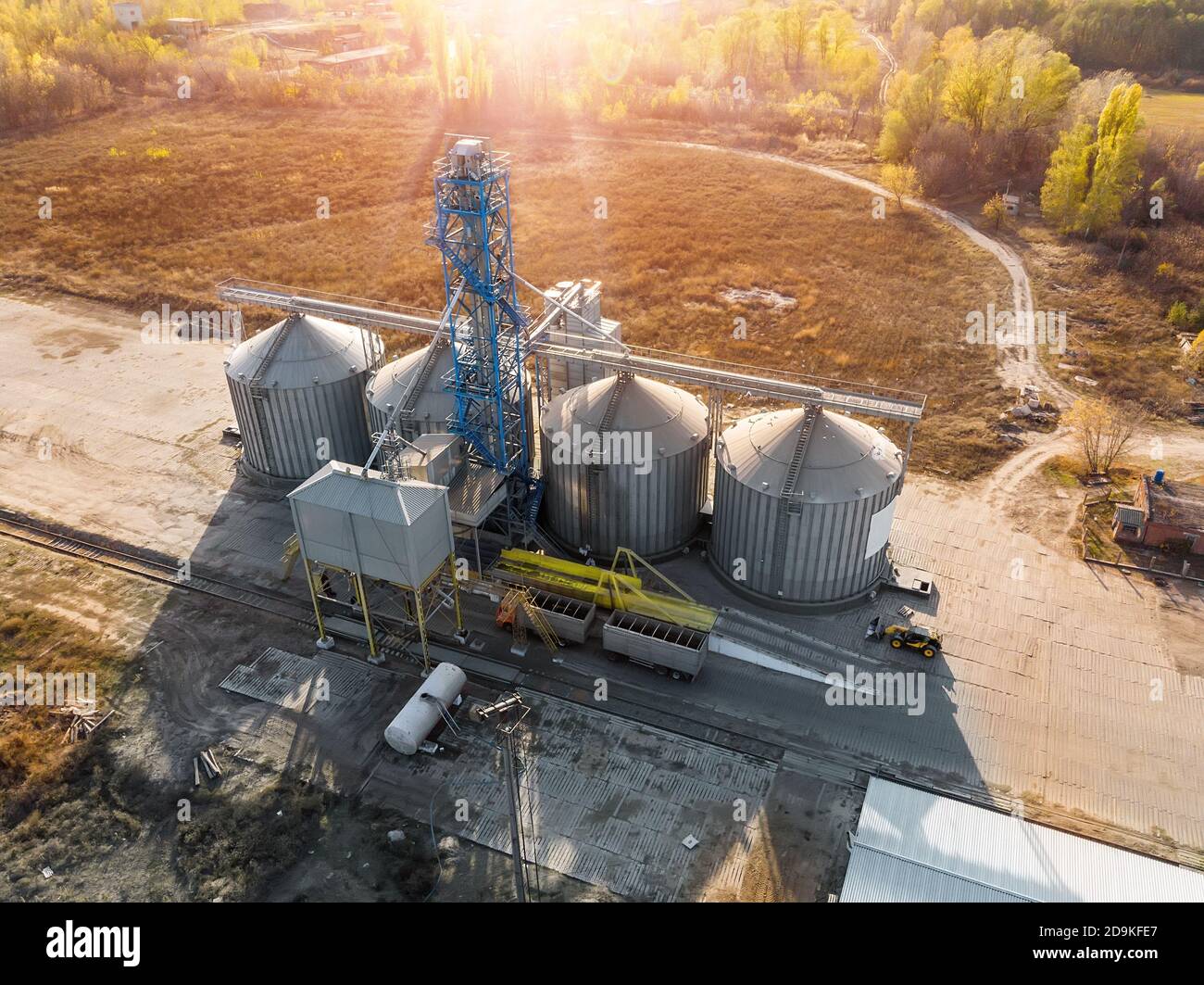 Aerial drone view modern steel agricultural grain granary silos cereal storage warehouse loading cargo grain carrier sunset. Agribuisness farmland Stock Photo