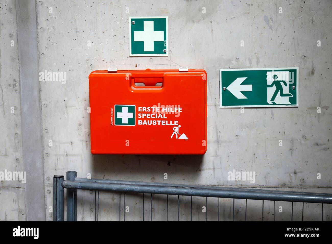 North Rhine-Westphalia, Germany, first aid kit on a concrete wall next to an emergency exit sign on a construction site, symbolic image of occupational safety. Stock Photo