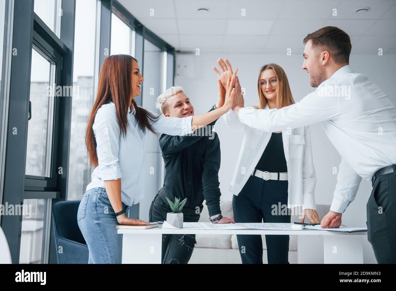 Group of young business people giving high five to each other in the ...