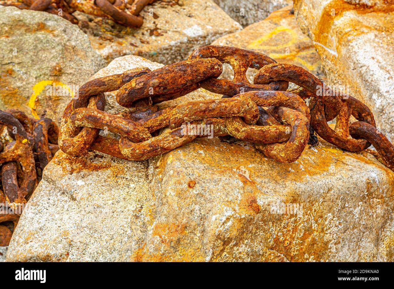 Old rusty anchor chain on a rock. Stock Photo