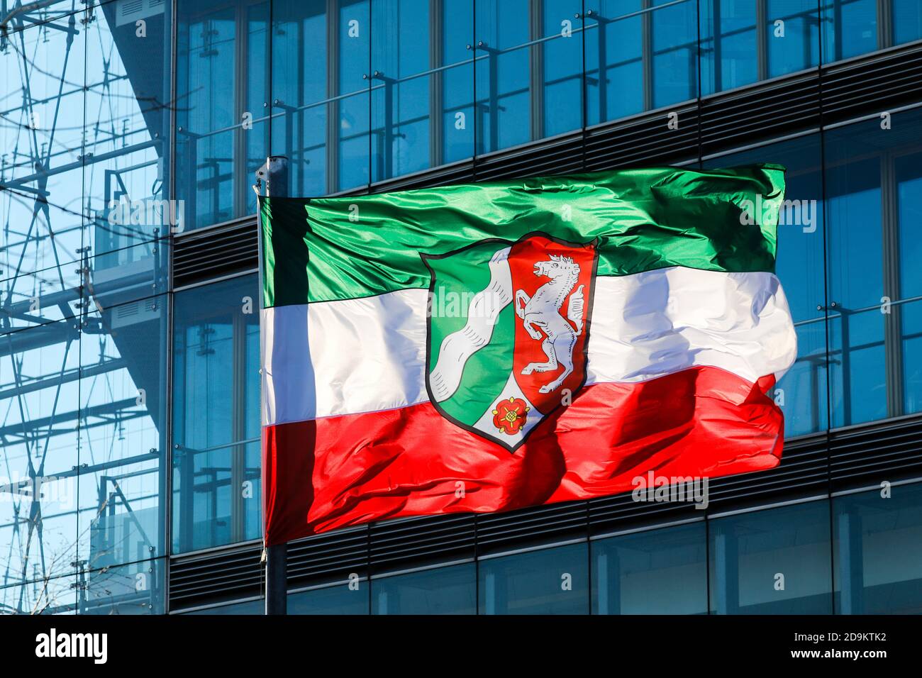 NRW North Rhine-Westphalia flag on flagpole blowing in the wind in front of the facade of the city gate, Düsseldorf, North Rhine-Westphalia, Germany Stock Photo
