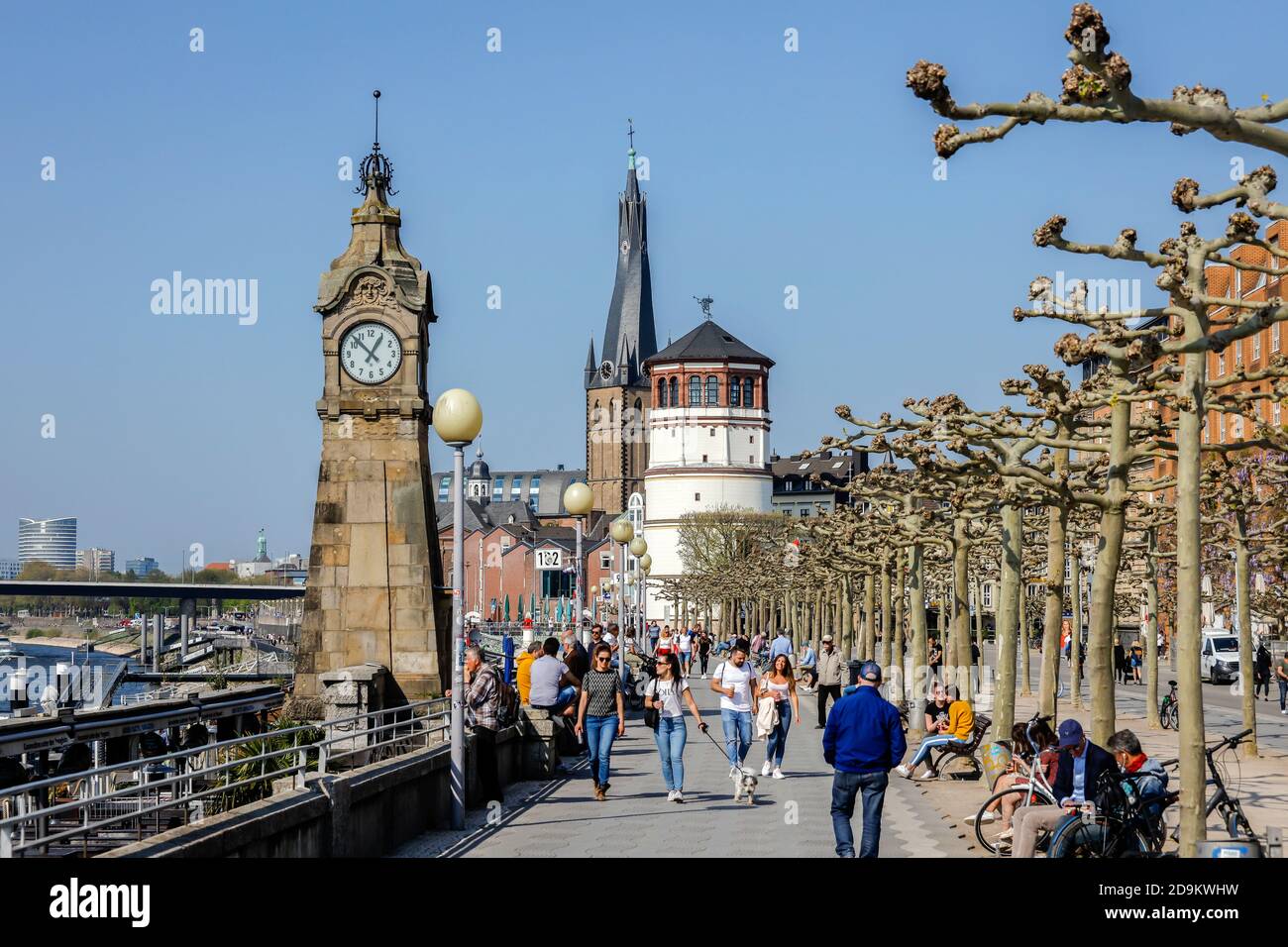 Duesseldorf, North Rhine-Westphalia, Germany, Rhine promenade at the level clock in times of the corona pandemic with ban on contact, in the back Basilica St. Lambertus and castle tower. Stock Photo