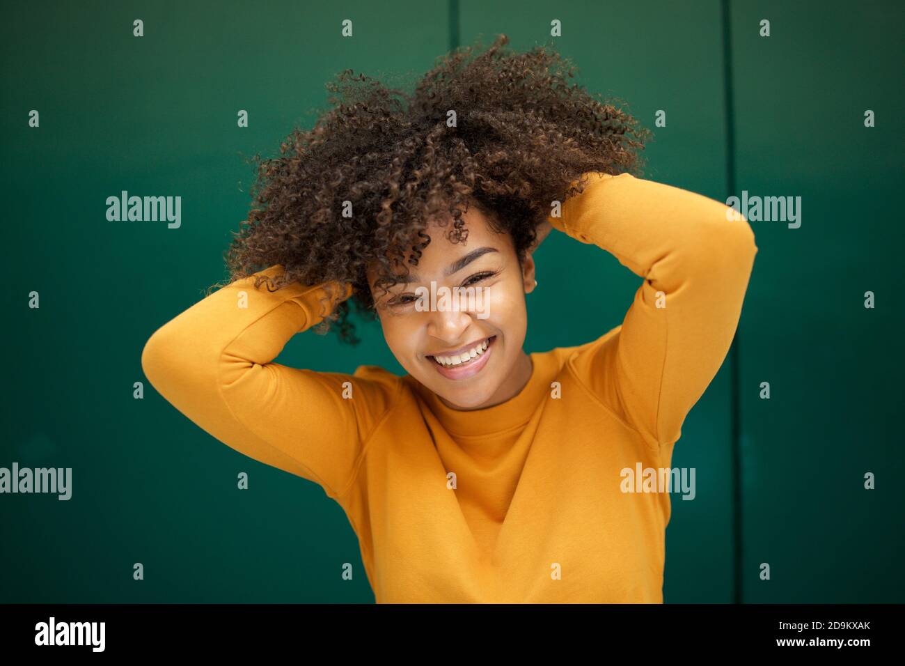Close up portrait smiling young African woman with hands in hair by ...