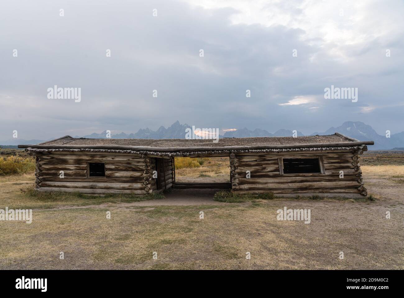 The old historic Cunningham ranch cabin in Grand Teton National Park was built of logs by J.P Cunningham in 1888.  Behind is Grand Teton and the Teton Stock Photo