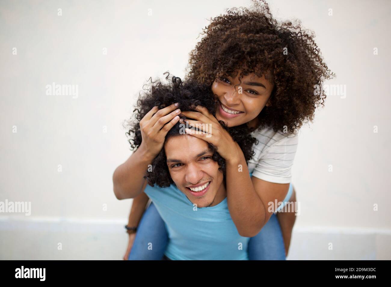 Cheerful woman holding on to boyfriends head while having piggyback ride  stock photo