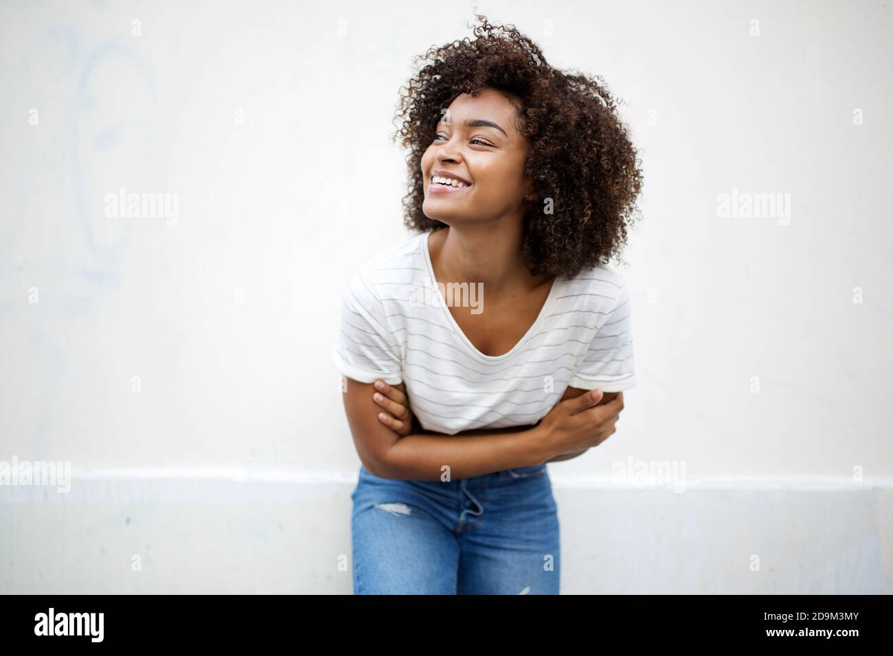 Portrait young african american woman with curly hair smiling by white ...