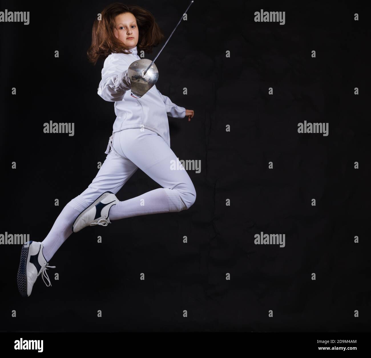Teenage girl fencer dressed in uniform with epee and helmet studio ...