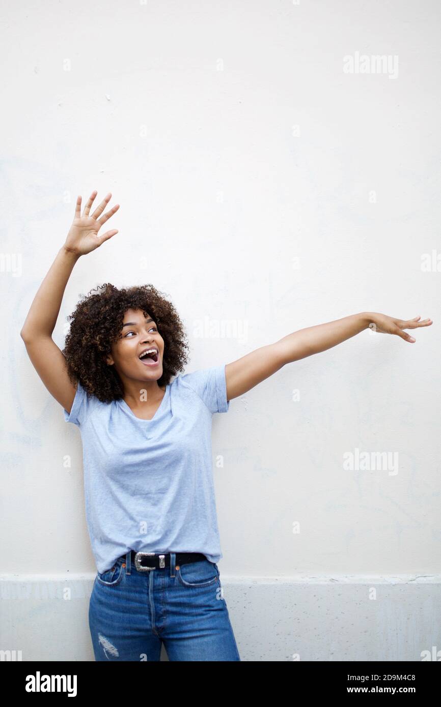 Portrait cheerful young african american woman with arms raised by ...