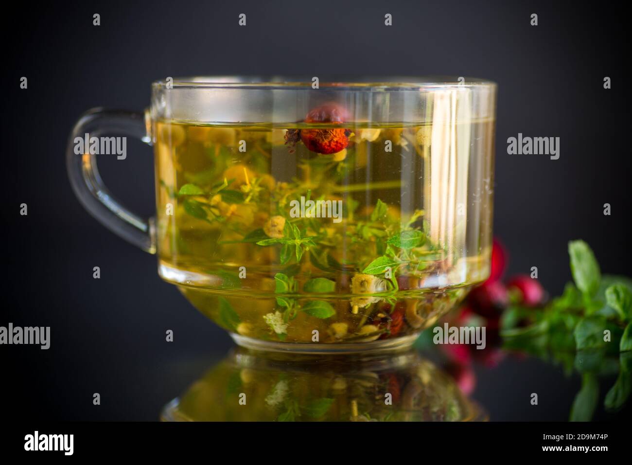 hot herbal tea from various herbs in glass cup on black background ...