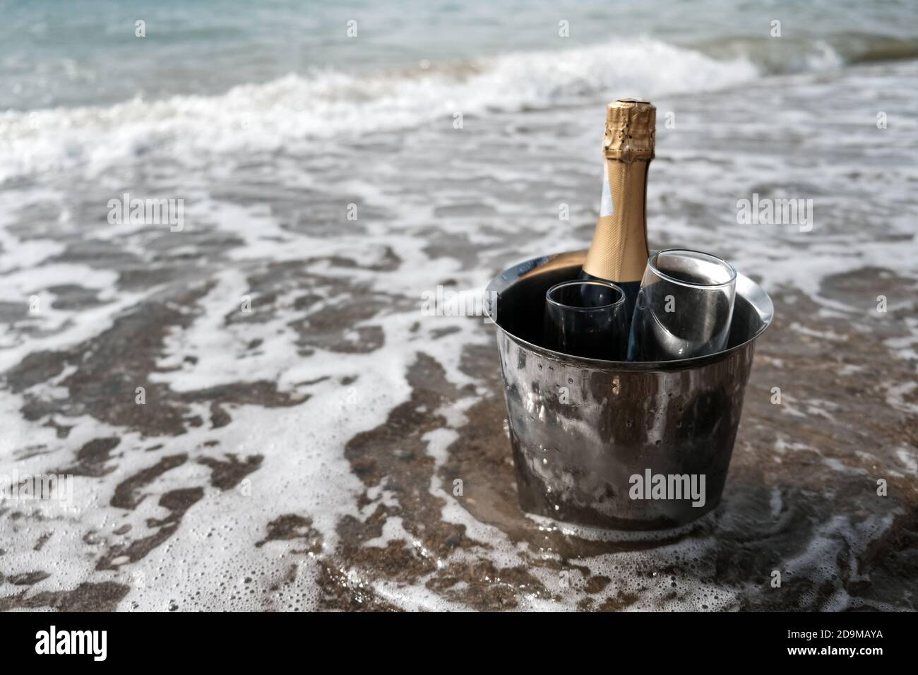 Ice bucket with champagne bottle and glasses on a beach surrounded by sea.  Ocean waves chilling drinks, luxury vacation for two. Anniversary day Stock  Photo - Alamy