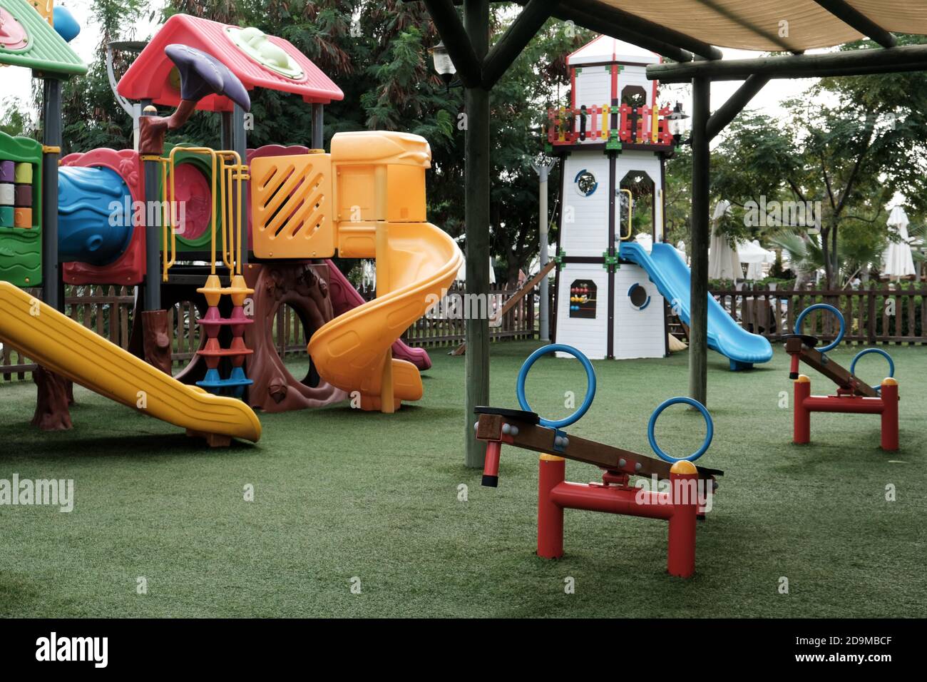 Empty swings in kindergarten. Playground closed for children in pandemic. Unattended slide and swing set during coronavirus outbreak. Nobody playing Stock Photo
