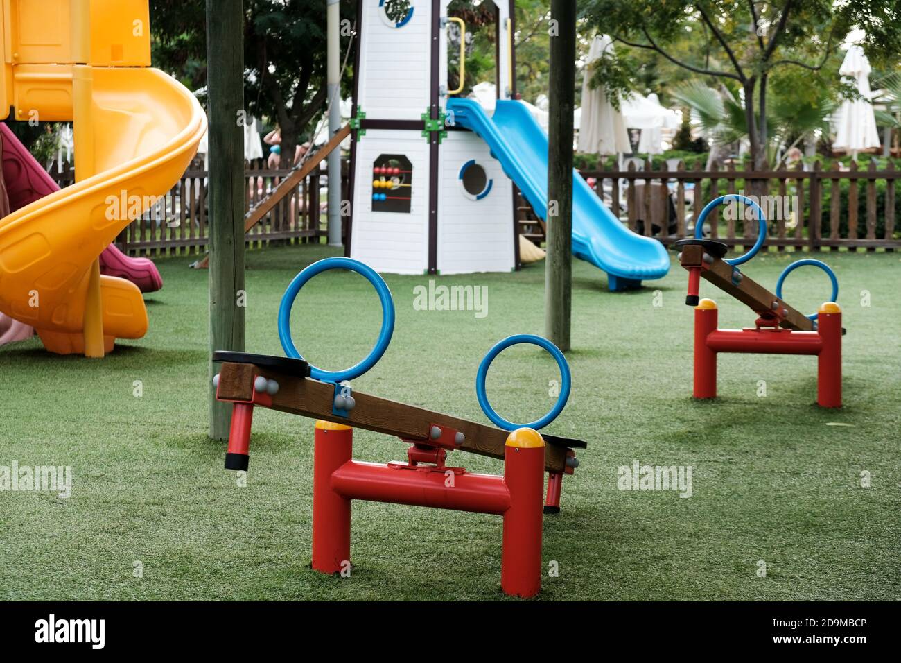Empty swings on kindergarten playground. Unattended slide and swing set during coronavirus outbreak. Closed for children in pandemic. Nobody playing Stock Photo