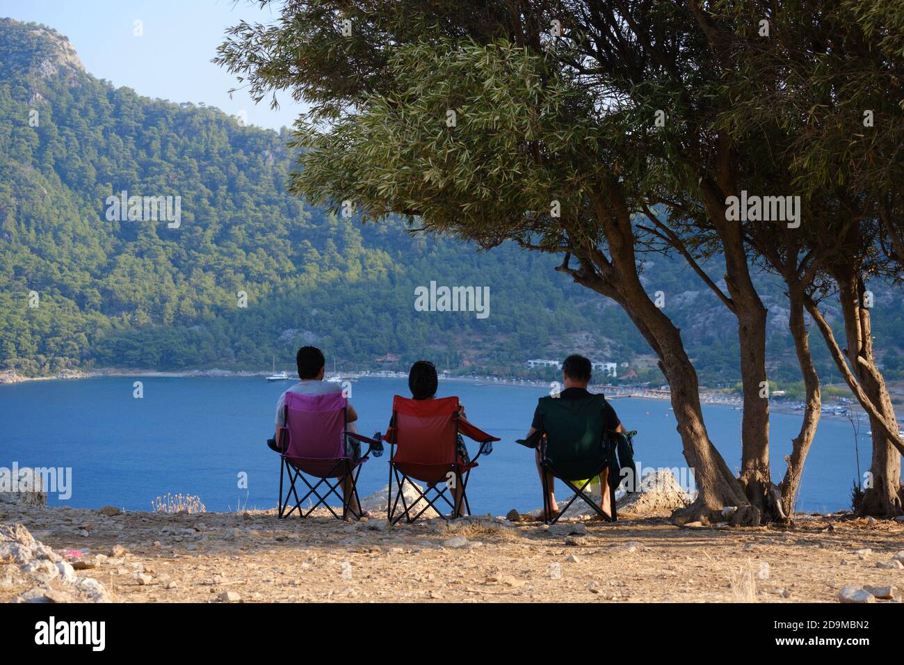 People sit in chairs and enjoy view of Kumlubuk beach and sea near Marmaris, Turkey Stock Photo