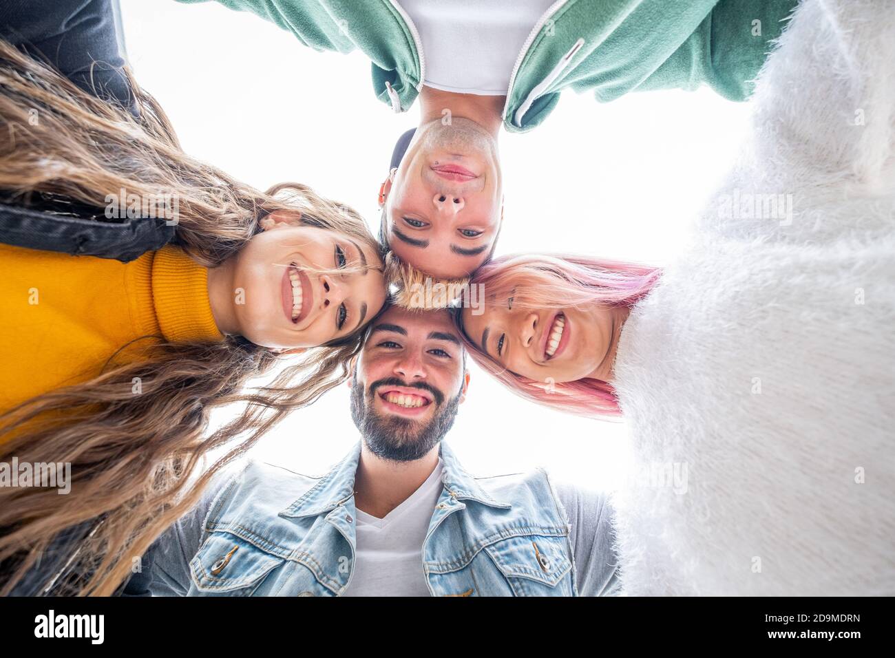 Group of four teenagers looking down arm in arm - Multicultural group of young people having fun - Friends on summer vacation looking at camera and la Stock Photo
