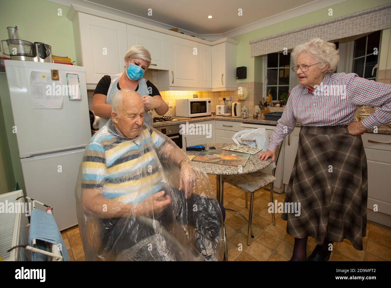 Elderly couple in their 80's at their home having tea served by a social care worker during the coronavirus pandemic lockdown, England, United Kingdom Stock Photo