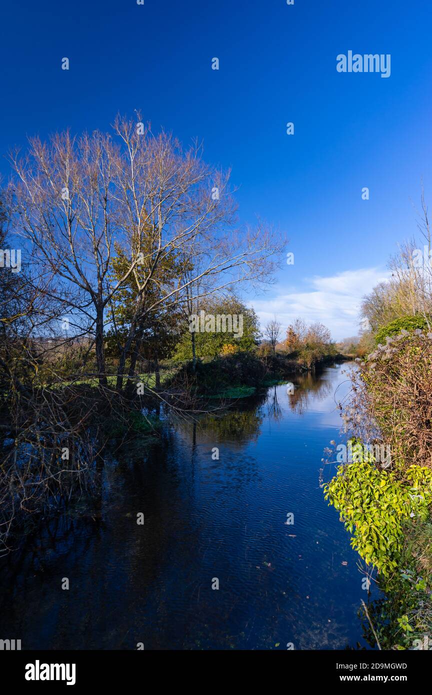 The river Itchen reflects blue skies on a sunny November day just outside the city of Winchester in Hampshire, England. Stock Photo