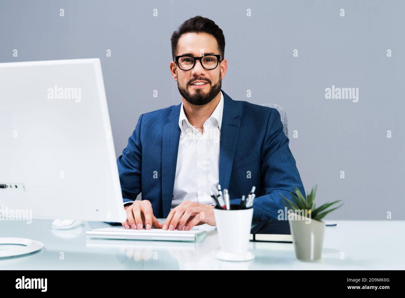 Smiling Business Man Working On Business Computer At Desk Stock Photo