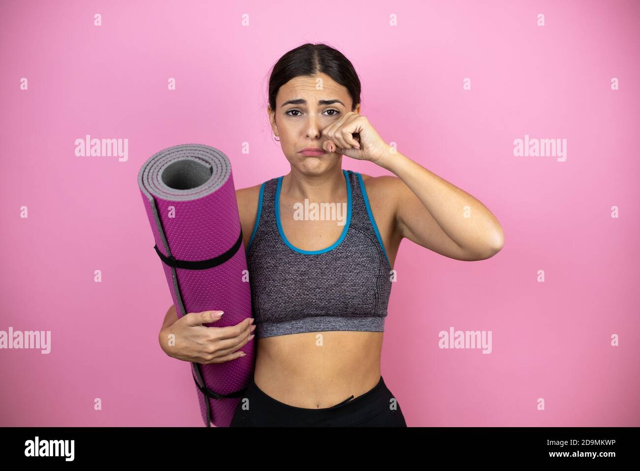 Young beautiful woman wearing sportswear over isolated pink background .depressed and worry for distress, crying angry and afraid. Sad expression. Hol Stock Photo