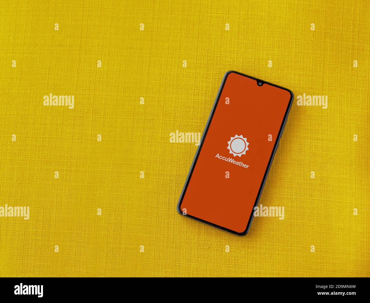 Lod, Israel - July 8, 2020: AccuWeather app launch screen with logo on the display of a black mobile smartphone on a yellow fabric background. Top vie Stock Photo