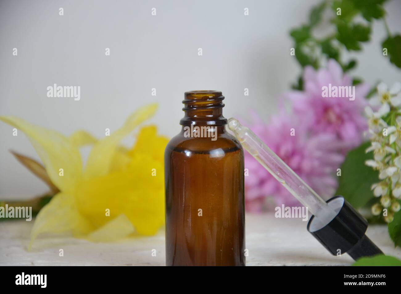 Bottles of essential aromatic or medical oils surrounded by fresh