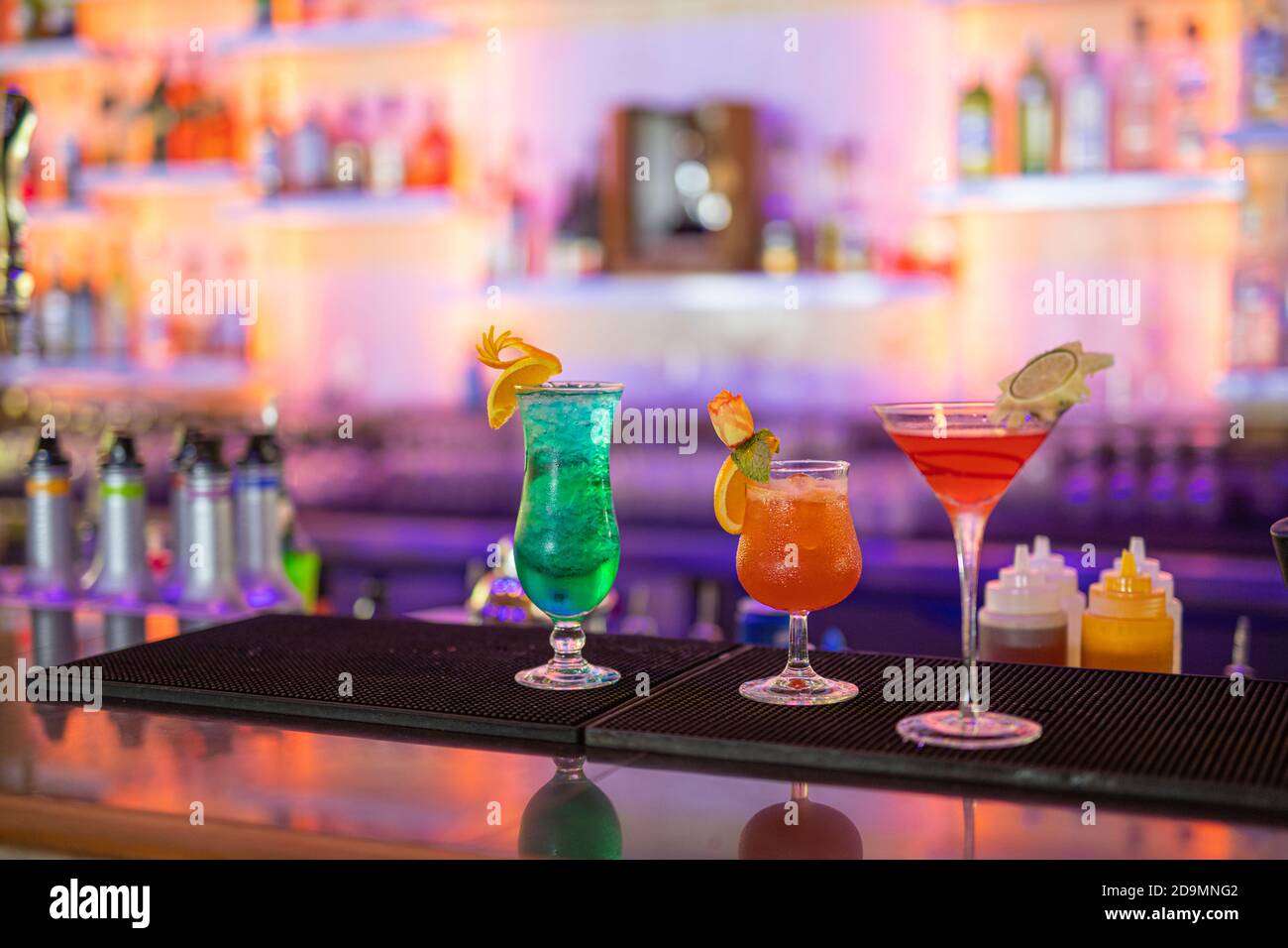 Colorful cocktails on bar counter. Tropical cocktails on restaurant table,  ready to serve. Nightlife party, bar drink background, blurred bottles  Stock Photo - Alamy