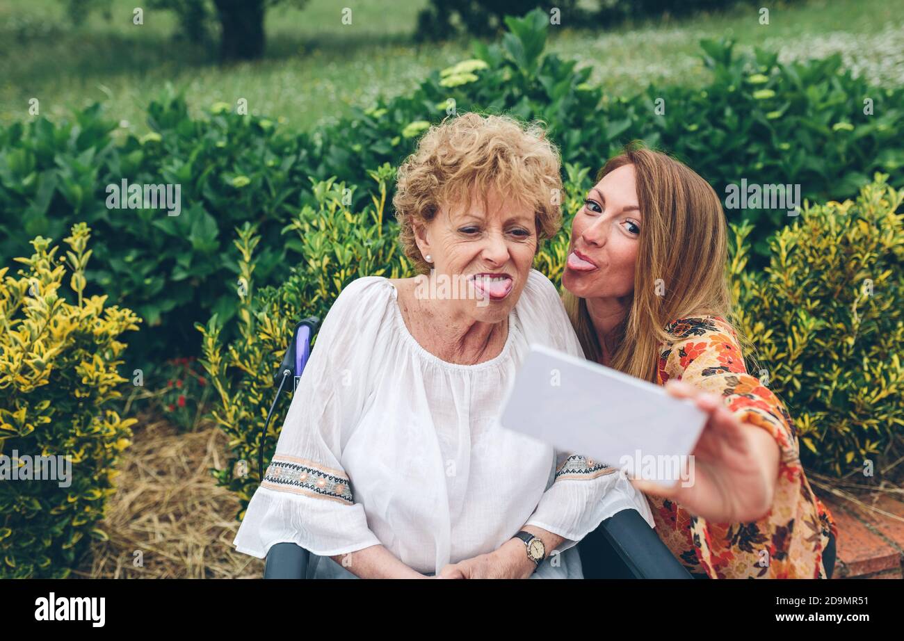 Girl taking selfie with her mother in wheelchair Stock Photo