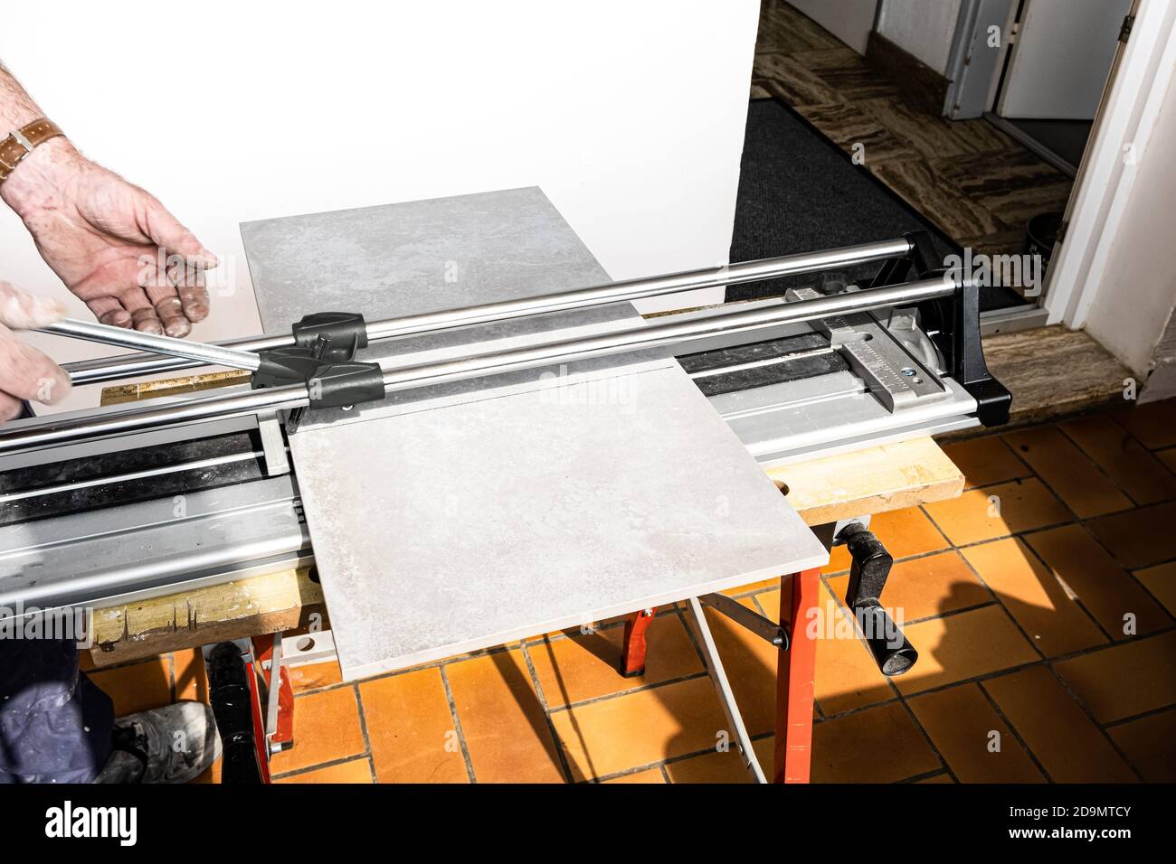 the mason cuts a ceramic tile with a tile cutter Stock Photo