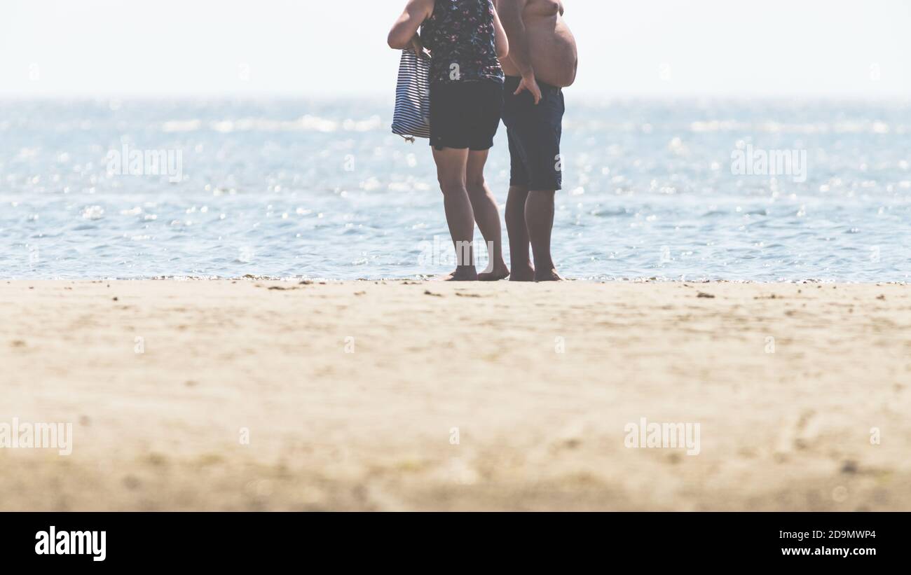 Headless: a woman and a man with a stomach, a couple enjoying the Wadden Sea and the North Sea, relaxation in St. Peter Ording. Stock Photo