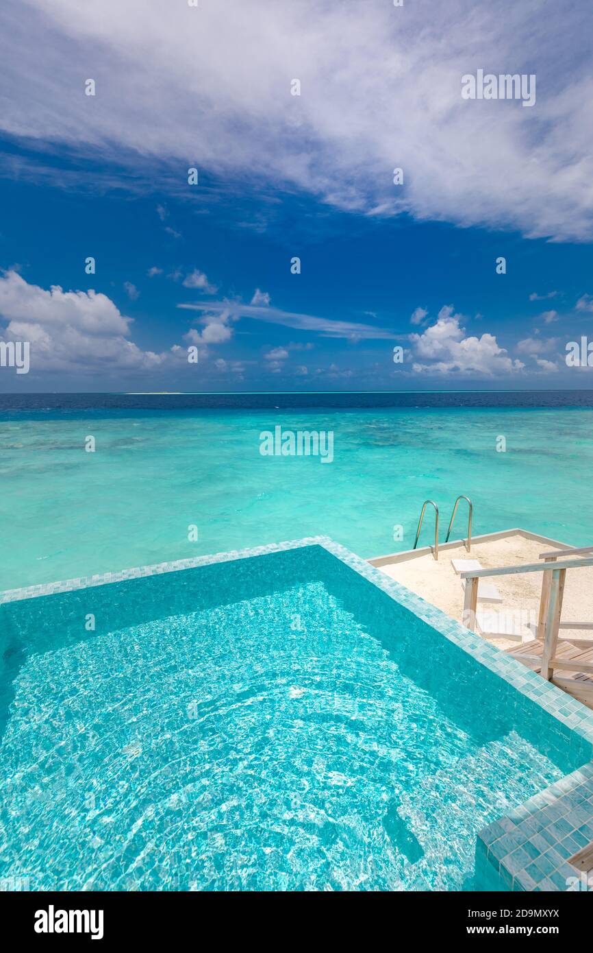 Infinity swimming pool with sea and ocean view on blue sky background. Luxury infinity pool over amazing turquoise lagoon and ladder into the water Stock Photo