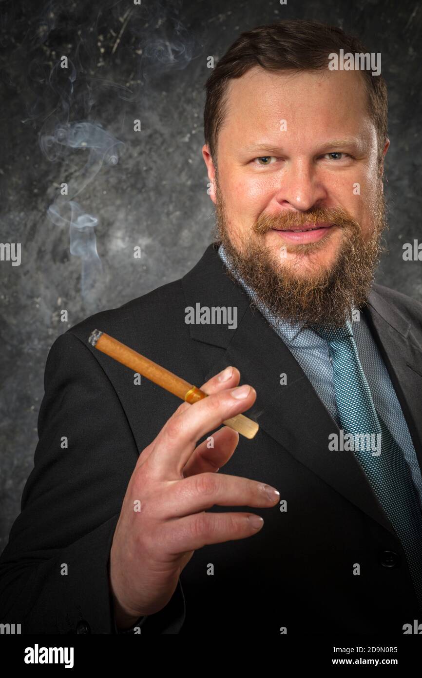 Solid smoling bearded man in suit with cigar studio portrait Stock Photo