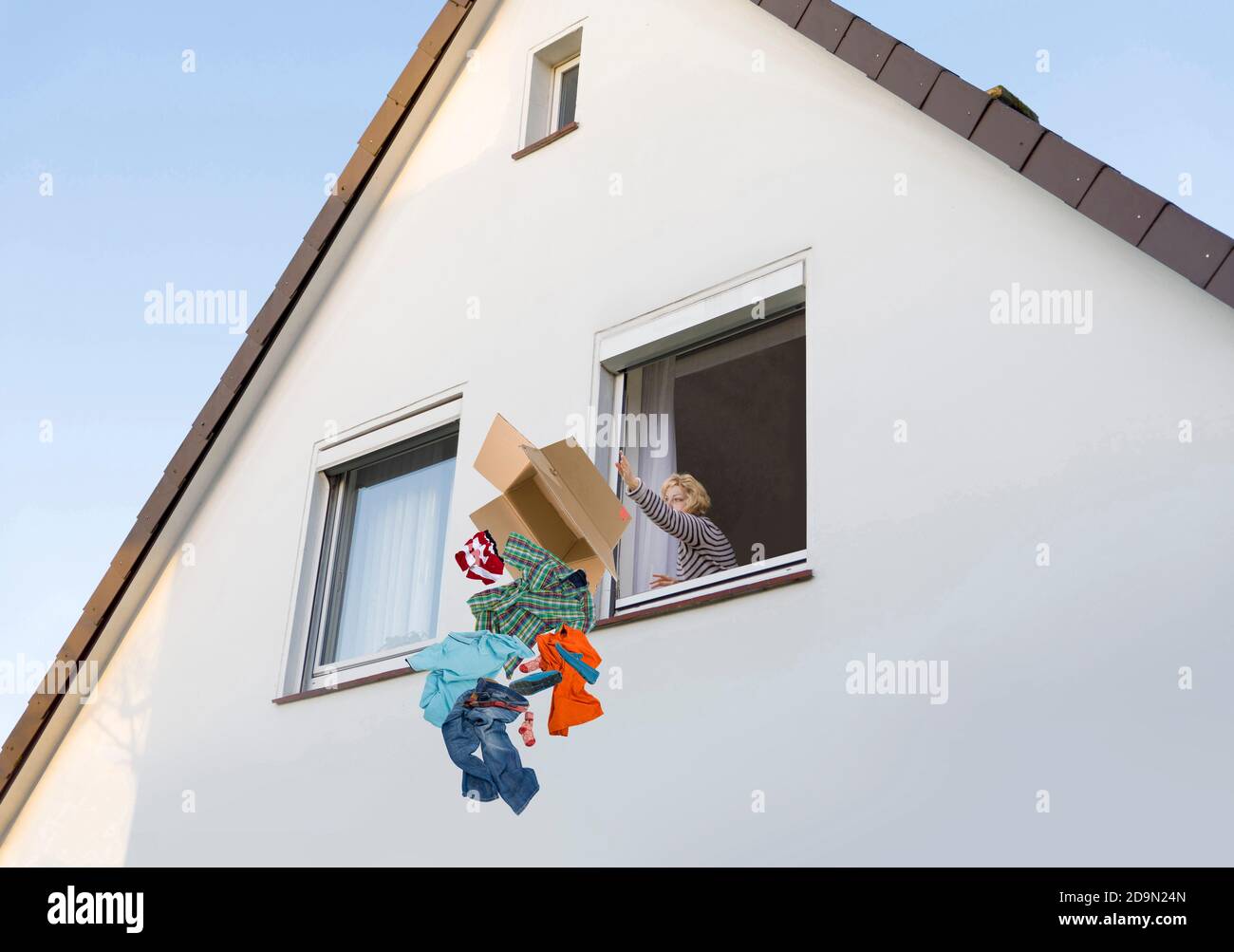 Woman throws her partner's clothes out of the window after the breakup Stock Photo