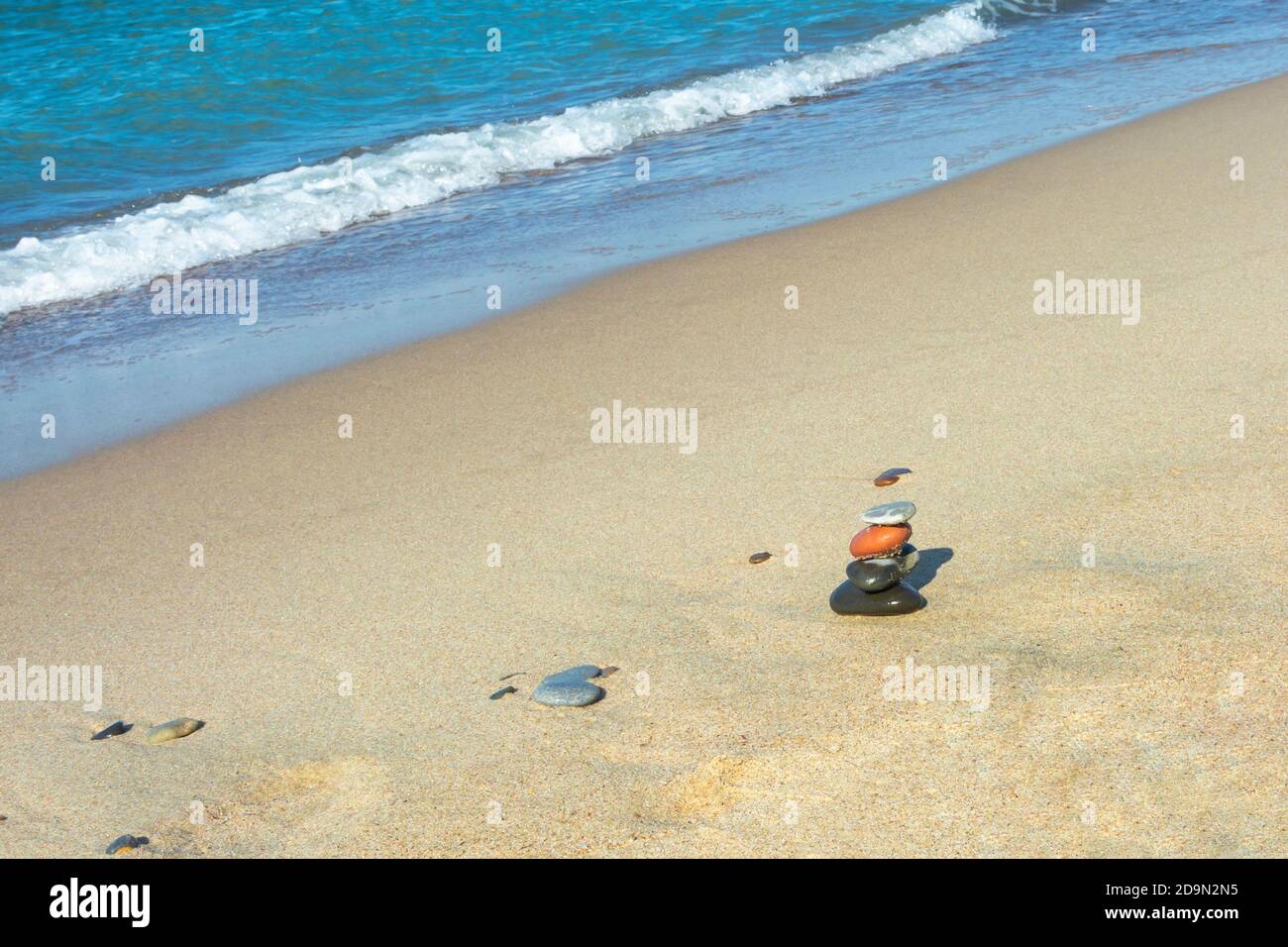 Pyramid of stones on sandy seashore. Harmony and meditation concept. Selective focus. Stock Photo