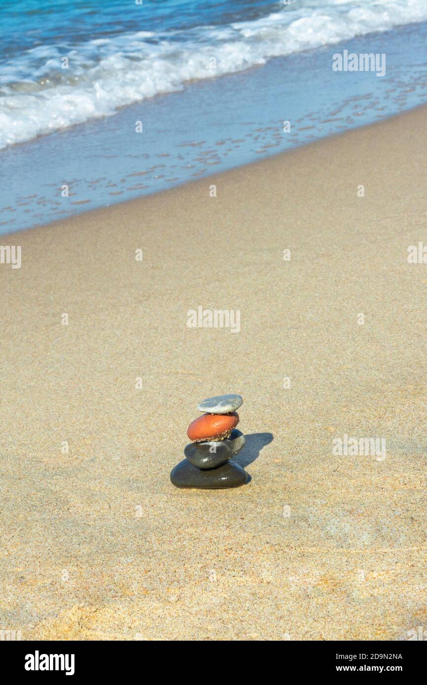 Stones in the pyramid are balanced on seashore. Harmony and meditation concept. Copy space, selective focus. Stock Photo