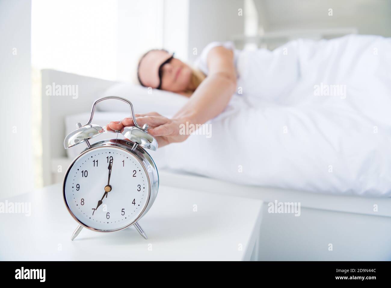Photo of aged lady woman lying sleeping bed white sheets turn off metal alarm clock ring seven o