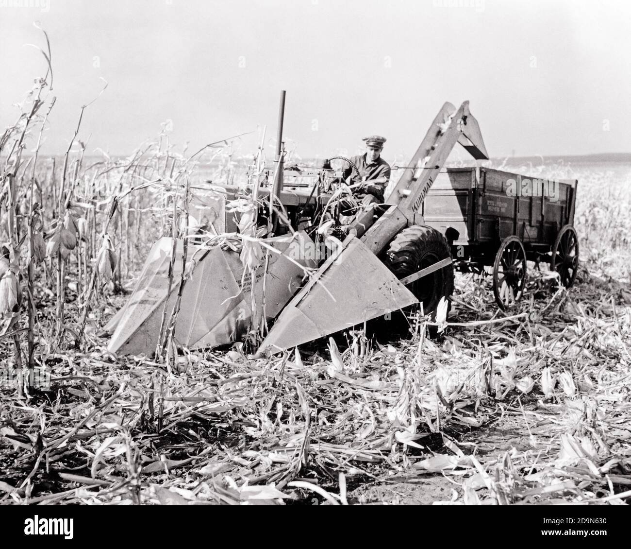 1940s SINGLE MAN FARMER DRIVING A TRACTOR AND CORN HARVESTER FARM