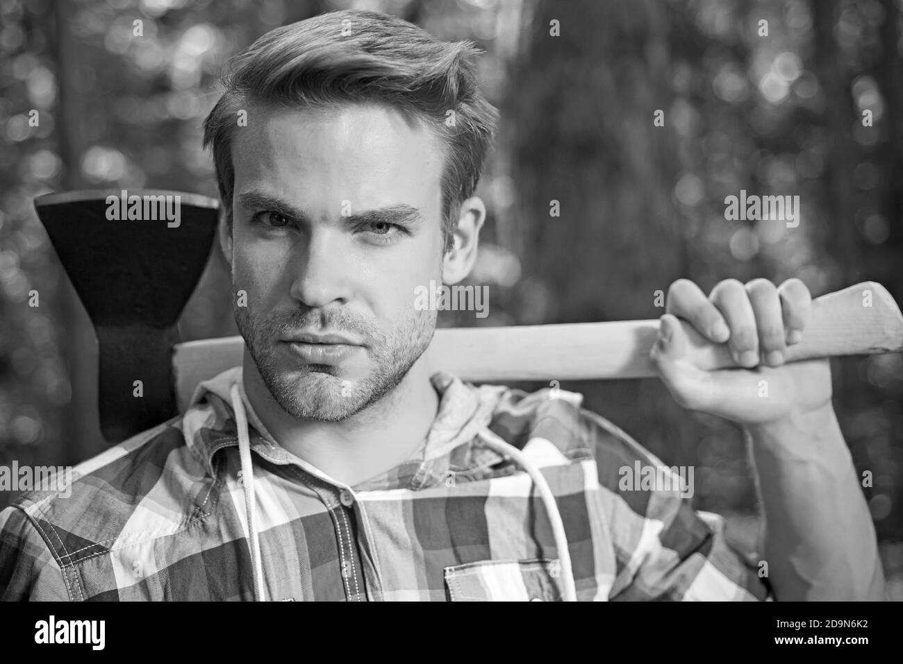 Lumberjack man carries axe on shoulder. Woodcutter with axe in the