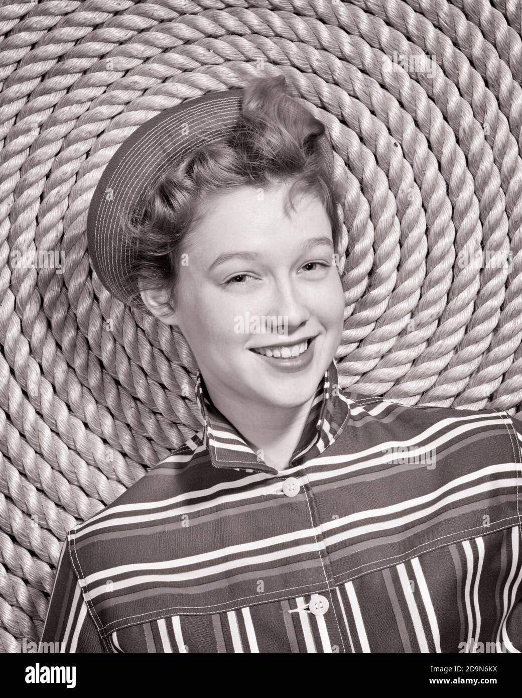 1960s SMILING YOUNG WOMAN SAILOR WEARING STITCHED CAP STRIPED SHIRT LOOKING AT CAMERA LEANING ON SPIRAL OF COILED NAUTICAL ROPE - g5074 HAR001 HARS OLD FASHION 1 JUVENILE FACIAL SAILING YOUNG ADULT PLEASED JOY LIFESTYLE SAILOR FEMALES STRIPED STUDIO SHOT HEALTHINESS COPY SPACE LADIES PERSONS TEENAGE GIRL NAUTICAL EXPRESSIONS B&W EYE CONTACT THEME HAPPINESS CHEERFUL RECREATION OF ON SMILES SPIRAL BOATING COILED JOYFUL TEENAGED PLEASANT FRESH-FACED JUVENILES STITCHED YOUNG ADULT WOMAN YOUNGSTER YOUTHFUL BLACK AND WHITE CAUCASIAN ETHNICITY HAR001 OLD FASHIONED Stock Photo