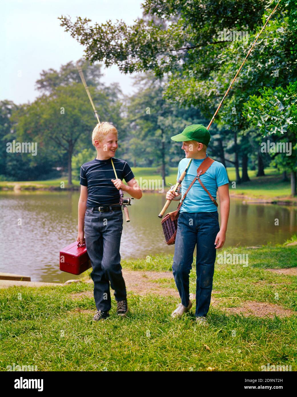 1970s TWO BOYS WALKING ALONG LAKESIDE TALKING CARRYING FISHING