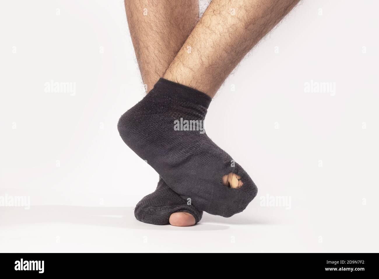 Closeup of the feet of a male wearing black socks with holes isolated on a  gray background Stock Photo - Alamy