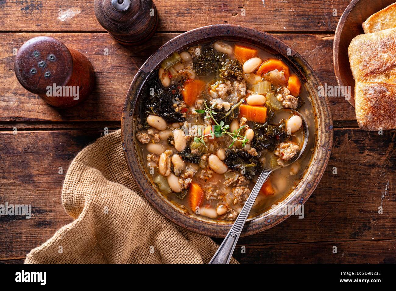 A bowl of delicious Italian sausage, kale and white bean cannellini soup with thyme garnish. Stock Photo