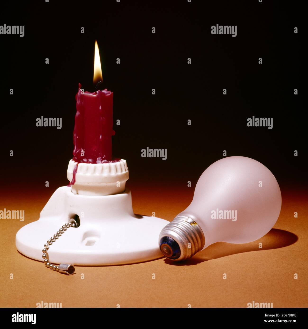 1970s RED CANDLE BURNING IN PORCELAIN ELECTRICAL LIGHT SOCKET WITH LIGHT BULB LYING ON SIDE - ks13521 HAR001 HARS RESOURCEFUL SOCKET SYMBOLIC APOCALYPSE CONCEPTS FAILURE SOLUTIONS SURVIVAL BLACKOUT CONSERVATION HAR001 OLD FASHIONED REPRESENTATION Stock Photo