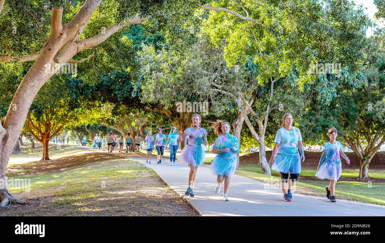 MACKAY, QUEENSLAND, AUSTRALIA - JUNE 2019: Unidentified woman and children wearing skirts running and walking in Color Frenzy Fun Run Stock Photo