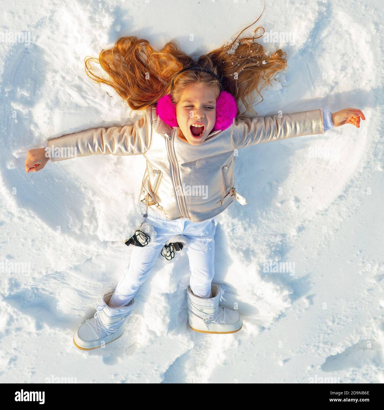 Girl on a snow angel shows. Smiling child lying on snow with copy space.  Funny kid making snow angel. Top view Stock Photo - Alamy